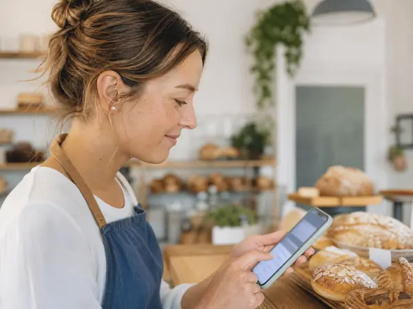 A bakery owner typing a question into an AI assistant on her phone